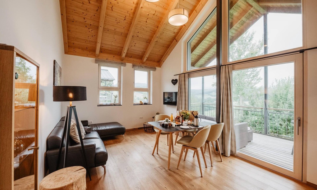 Bohmzwiesel Apartment | Ferienchalet mit überdachter Veranda mit Lounge Möbel und Schwebeliege.