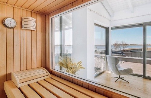 Waase Apartment | FISCHER:IN Vacation Rental in Ummanz. Panoramic sauna with a stunning view of the water. Spacious sun deck for relaxing vacation moments. The ultimate in sleeping comfort with box-spring beds. Insect Screen