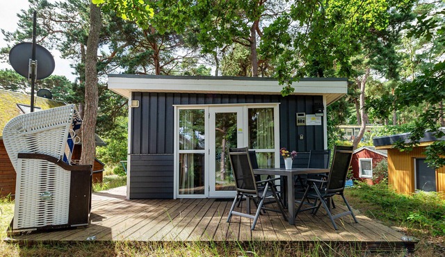 Achtern Dieck 68e Vacation Home in Baabe. A sunny terrace with its own beach chair and an idyllic view of the Baltic Sea through the trees. Comfortable living with underfloor heating